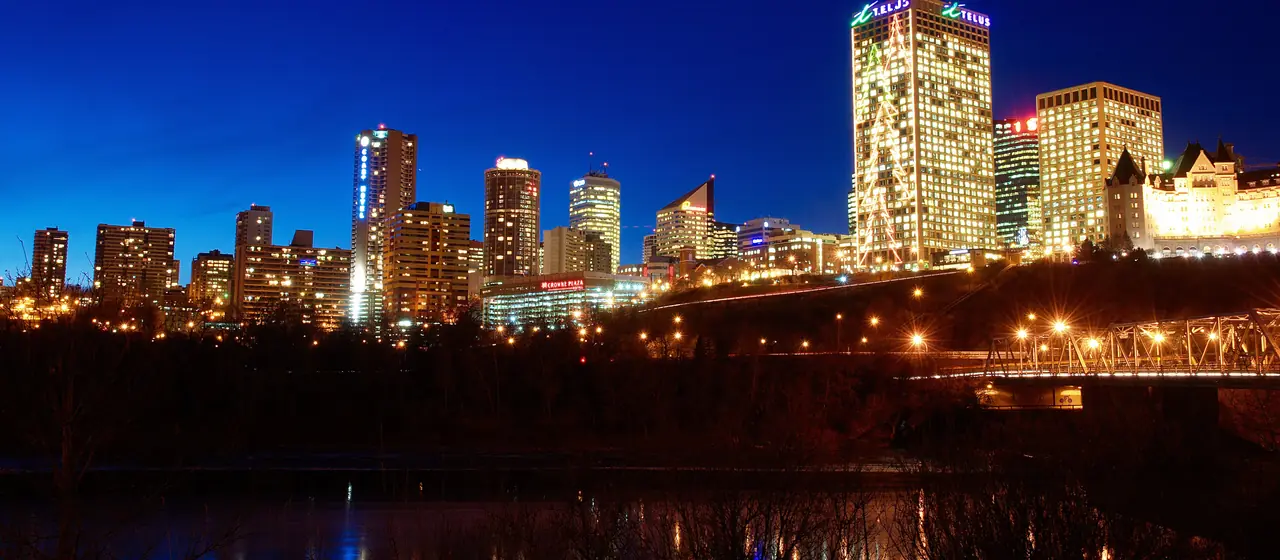 Downtown Edmonton's lit-up skyline at night, seen from across the river on the south side