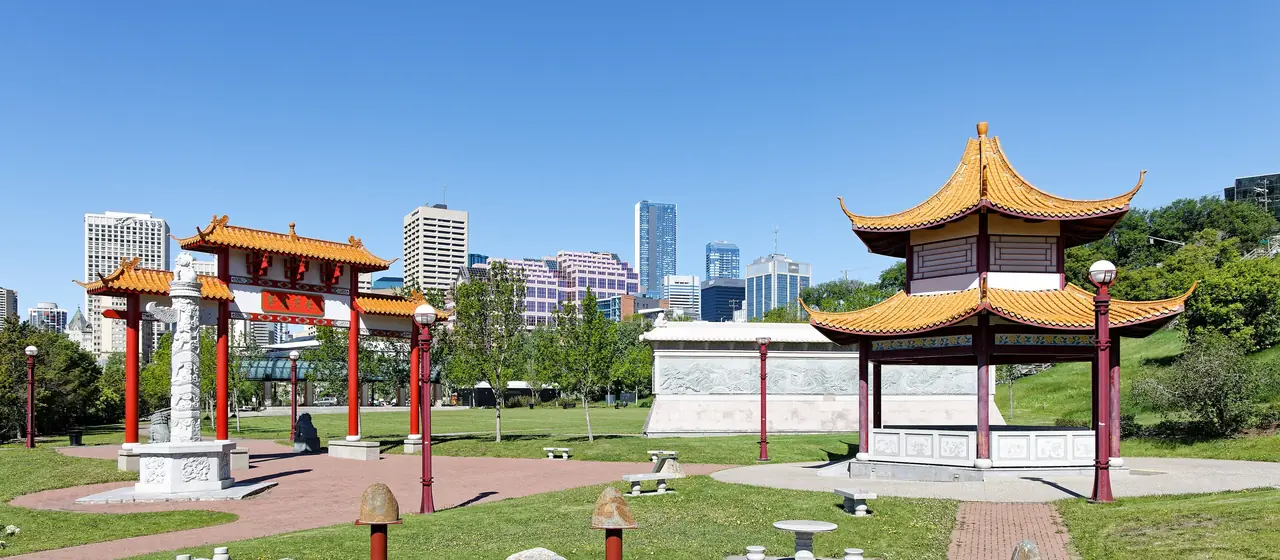 The Chinese Garden gate and pavilion in Louise McKinney Riverfront Park with downtown Edmonton towers behind