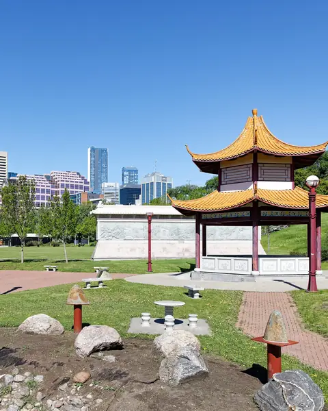 The Chinese Garden gate and pavilion in Louise McKinney Riverfront Park with downtown Edmonton towers behind