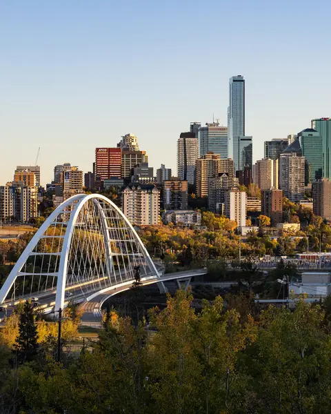 The white arch of the Walterdale Bridge crossing the river valley into the downtown Edmonton skyline in early autumn